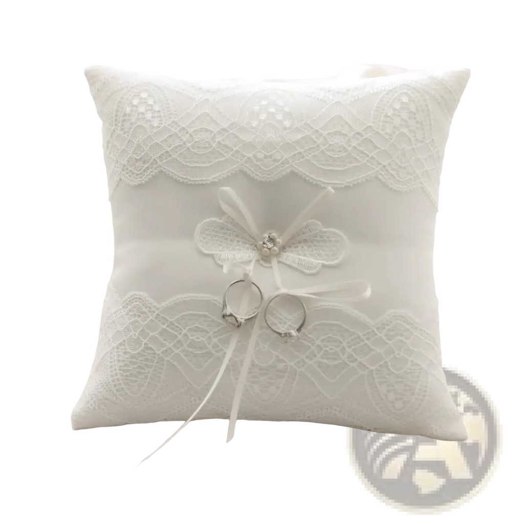 White lace wedding ring pillow with delicate floral bow and two rings nestled in soft fabric for ribbon bearer use