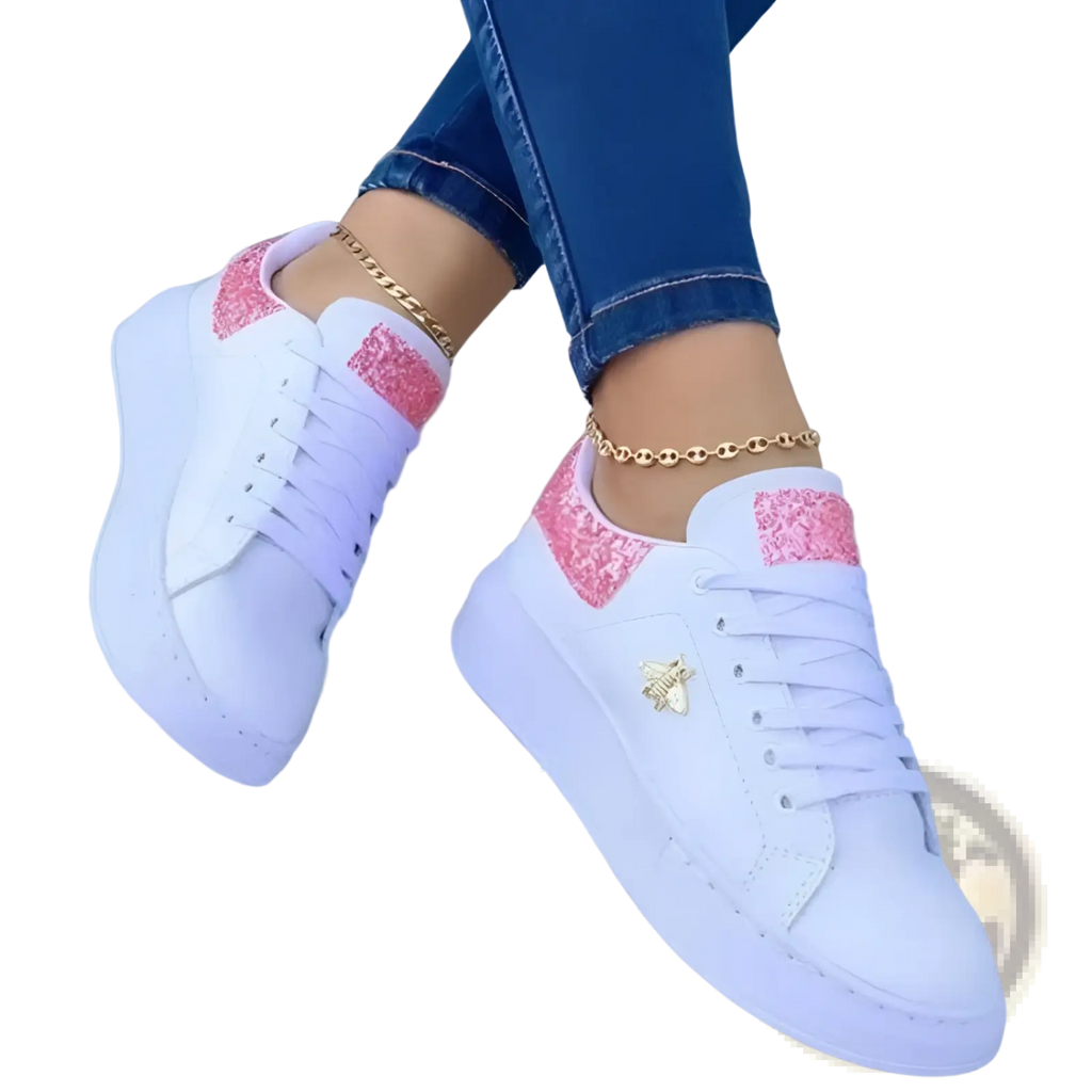 White platform sneakers with pink glitter accents and a gold bee emblem on the side in a stylish design