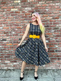 A black floral print sleeveless midi dress with a yellow belt by white rabbit suitable for casual occasions