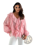 A soft pink sheer blouse with layered ruffles at the neckline and puff sleeves in a white ruffled v neck style