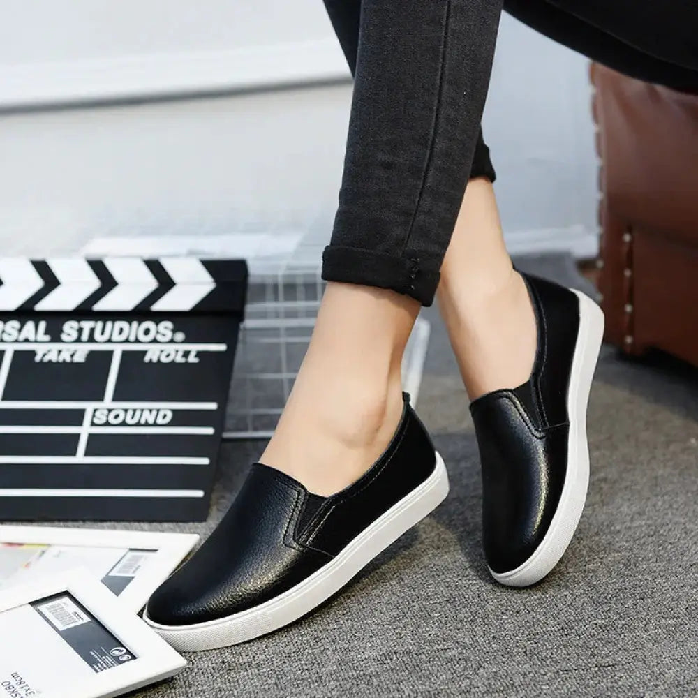 Black women’s minimalist Korean style leather slip-on sneakers with smooth leather upper and white rubber sole