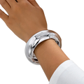 Wide gold bangle bracelet for women with sleek silver finish smooth reflective surface and subtle geometric contours