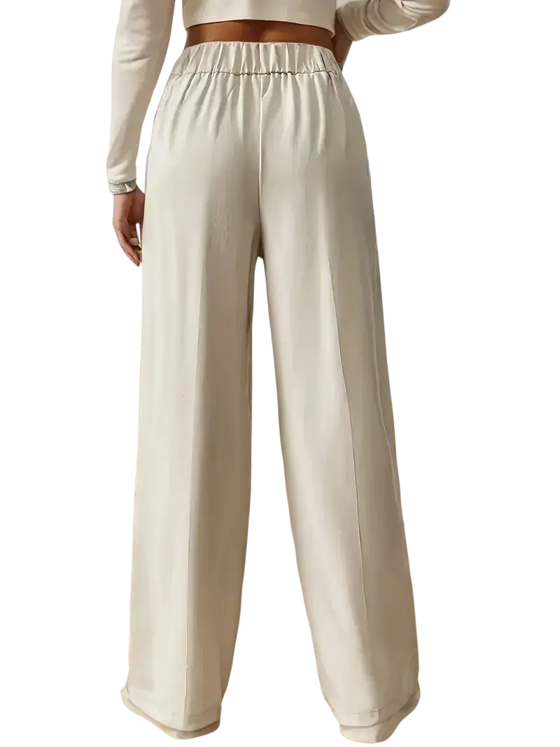 Cream-colored wide leg high waisted trousers with elastic waistband and satin-like smooth finish