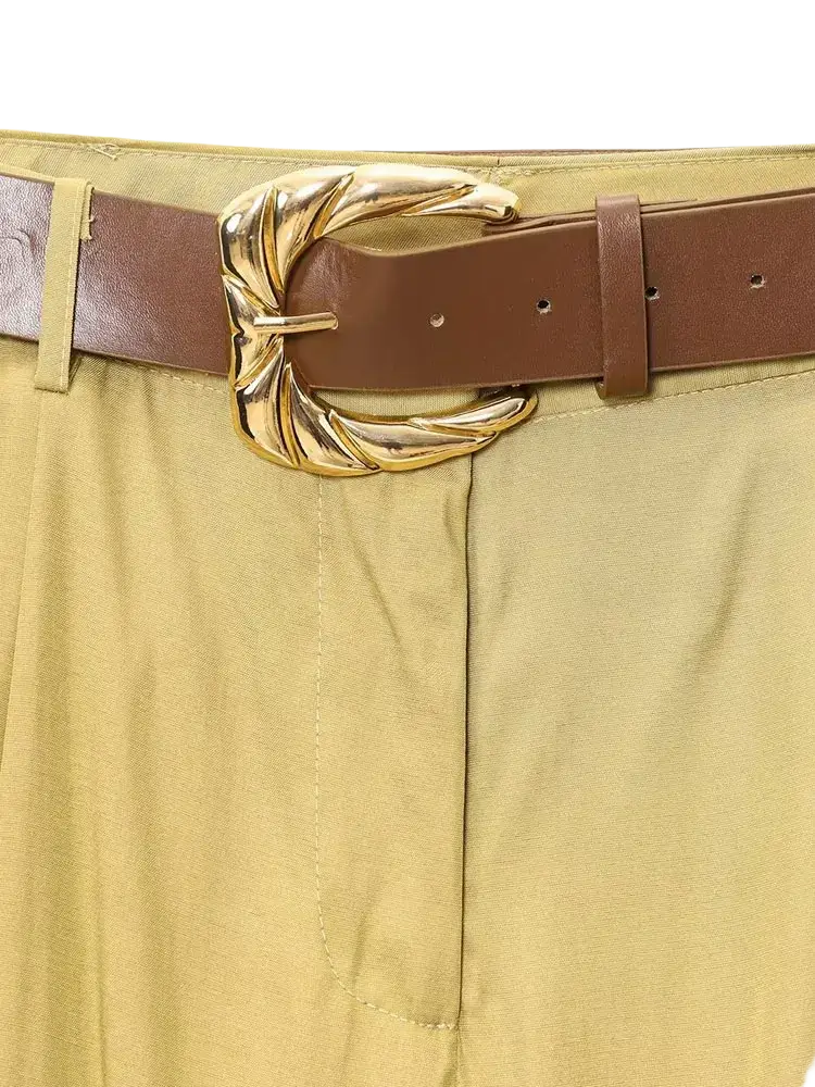 A brown leather belt with an ornate gold-tone leaf buckle paired with yellow wide leg pants for women