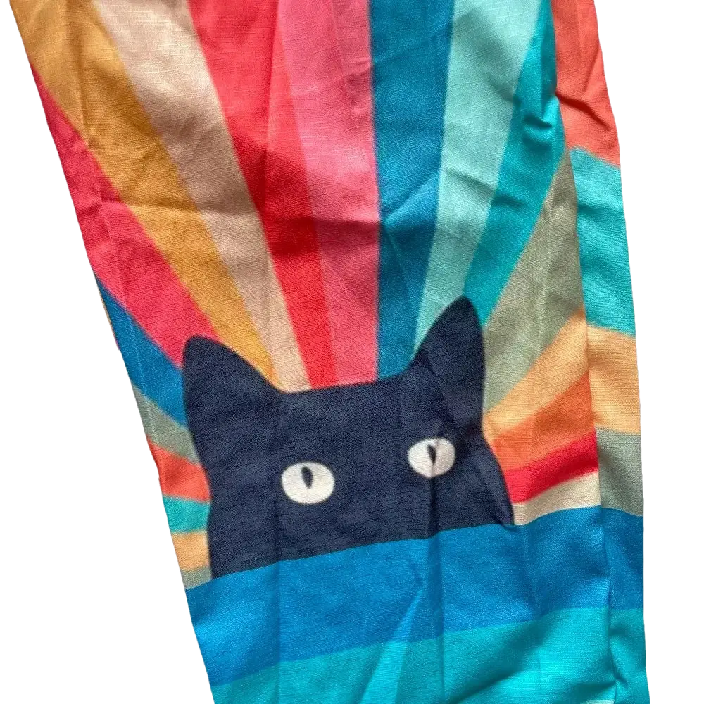 A navy blue cat with white eyes peeks from rainbow fabric near vintage blue leaf print wide leg pants casual trousers
