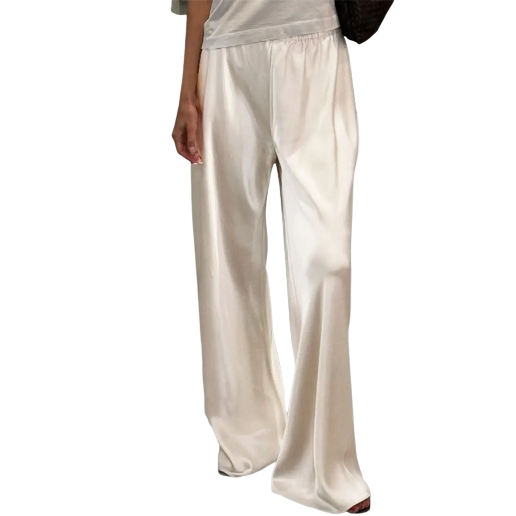 Cream wide leg satin pants with elastic waist featuring a relaxed flowing silhouette and full pants length