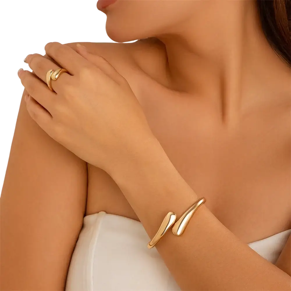 Gold-toned wide metal bangle with a sleek open-ended design and smooth curved surface in a chunky cuff style
