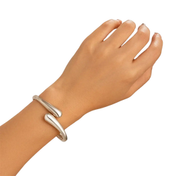 Silver color chunky wide metal bangle with smooth teardrop-shaped curves in an open cuff bracelet design