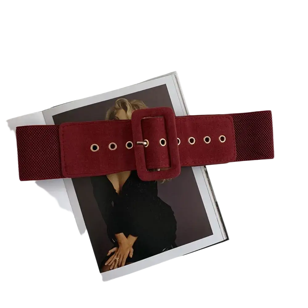 A wide burgundy suede elastic belt with a matching buckle and silver eyelets for women’s waist dress accessory