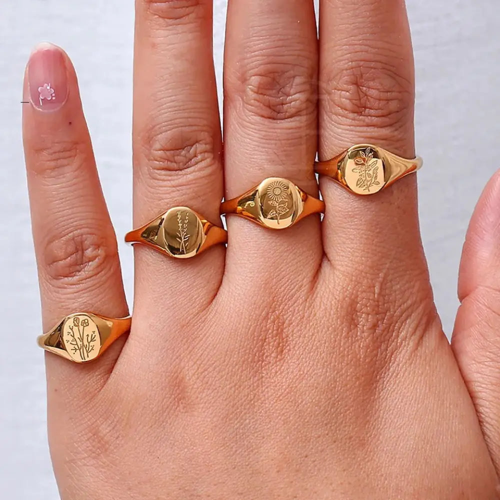 Set of five gold-toned wildflower engraved signet rings with smooth oval faces in a gold signet ring set