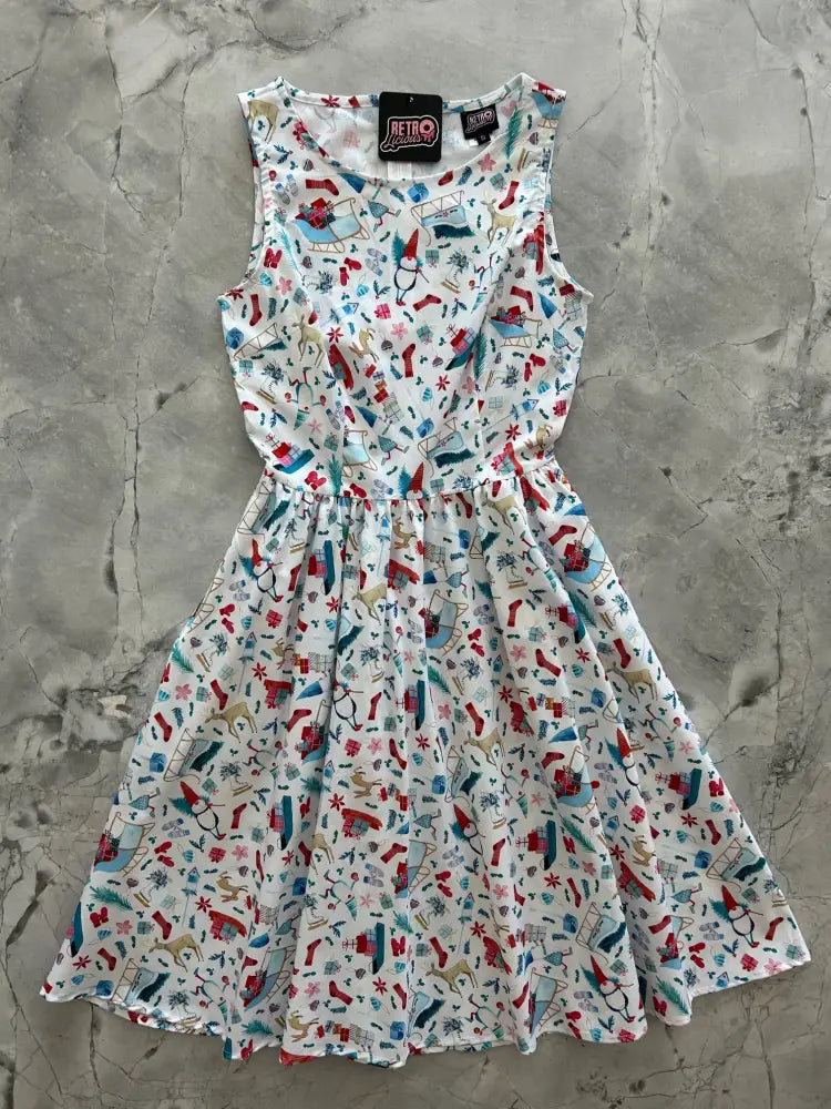 A sleeveless white vintage 1950s cotton Christmas dress with a festive pattern of stockings snowmen and ornaments