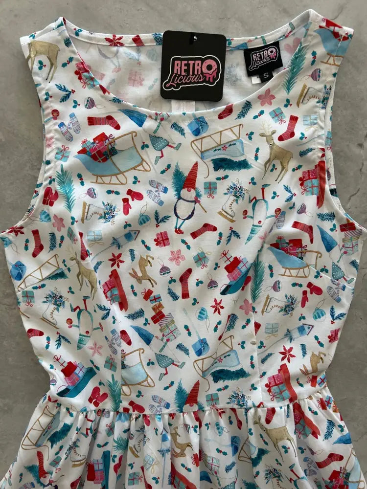 A festive white sleeveless vintage 1950s cotton Christmas dress with colorful reindeer sleigh and snowman print