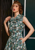 A vintage-inspired sleeveless cotton blouse with green and white floral pattern and a bow at the neckline