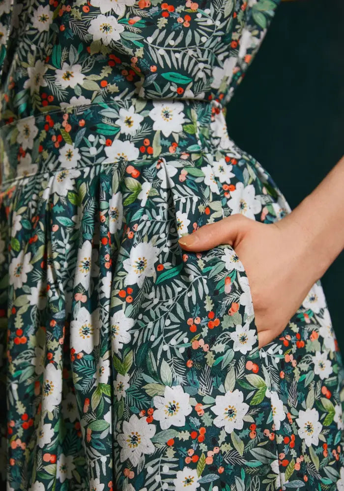 Winter floral doris retro cotton midi skirt in dark green with white blossoms orange berries and pockets featuring a botanical print