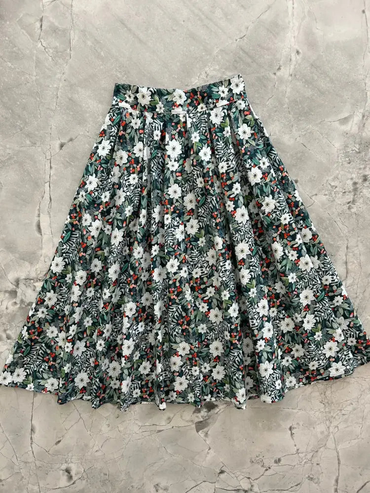 Winter floral Doris retro cotton midi skirt with pockets featuring a flared vibrant floral pattern on dark green fabric