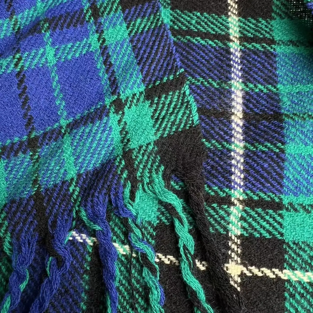 A cozy winter plaid viscose scarf in bold blue and green with black accents and fringe trim neck warmer