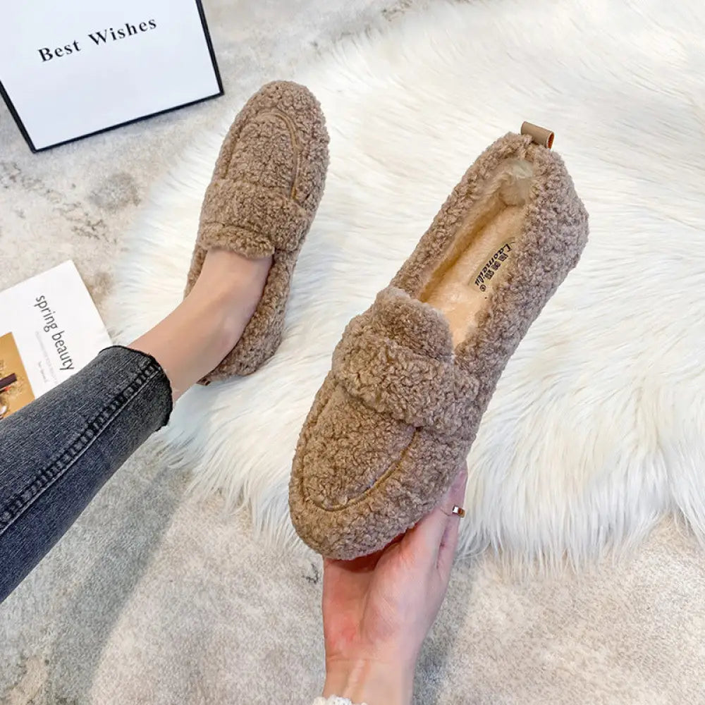 Beige plush faux shearling winter loafers with a soft fuzzy texture and small leather tab at the heel shown from the back