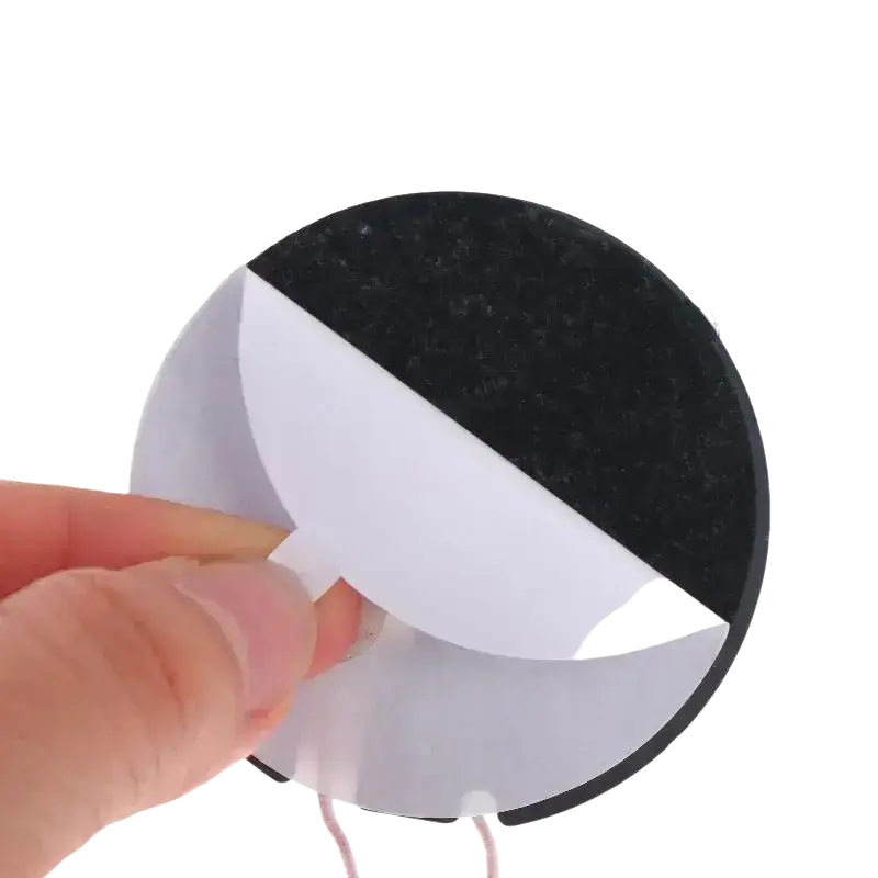 Black and white circular adhesive sticker with textured surface on the back side of a wireless charger module pcba board
