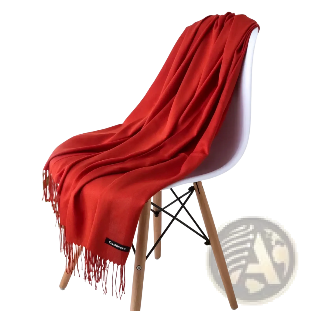 A vibrant red women cashmere feel winter scarf shawl with delicate fringe draped over a modern white chair