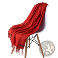 A vibrant red women cashmere feel winter scarf shawl with delicate fringe draped over a modern white chair
