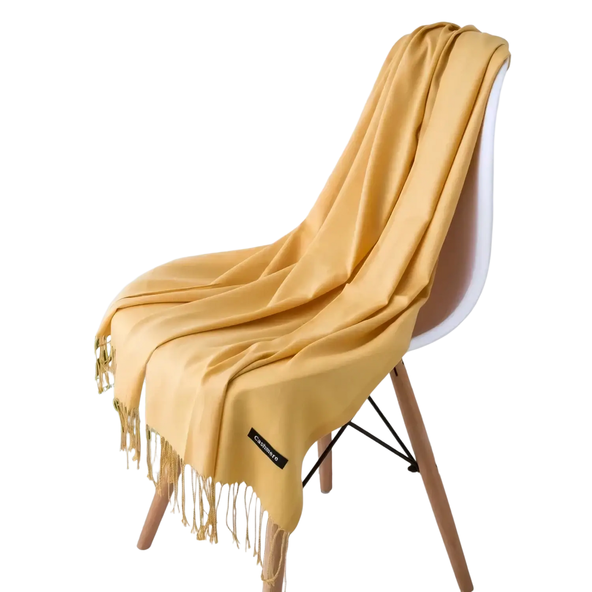 A soft mustard-yellow women cashmere feel winter scarf shawl with delicate gold fringe draped over a white chair