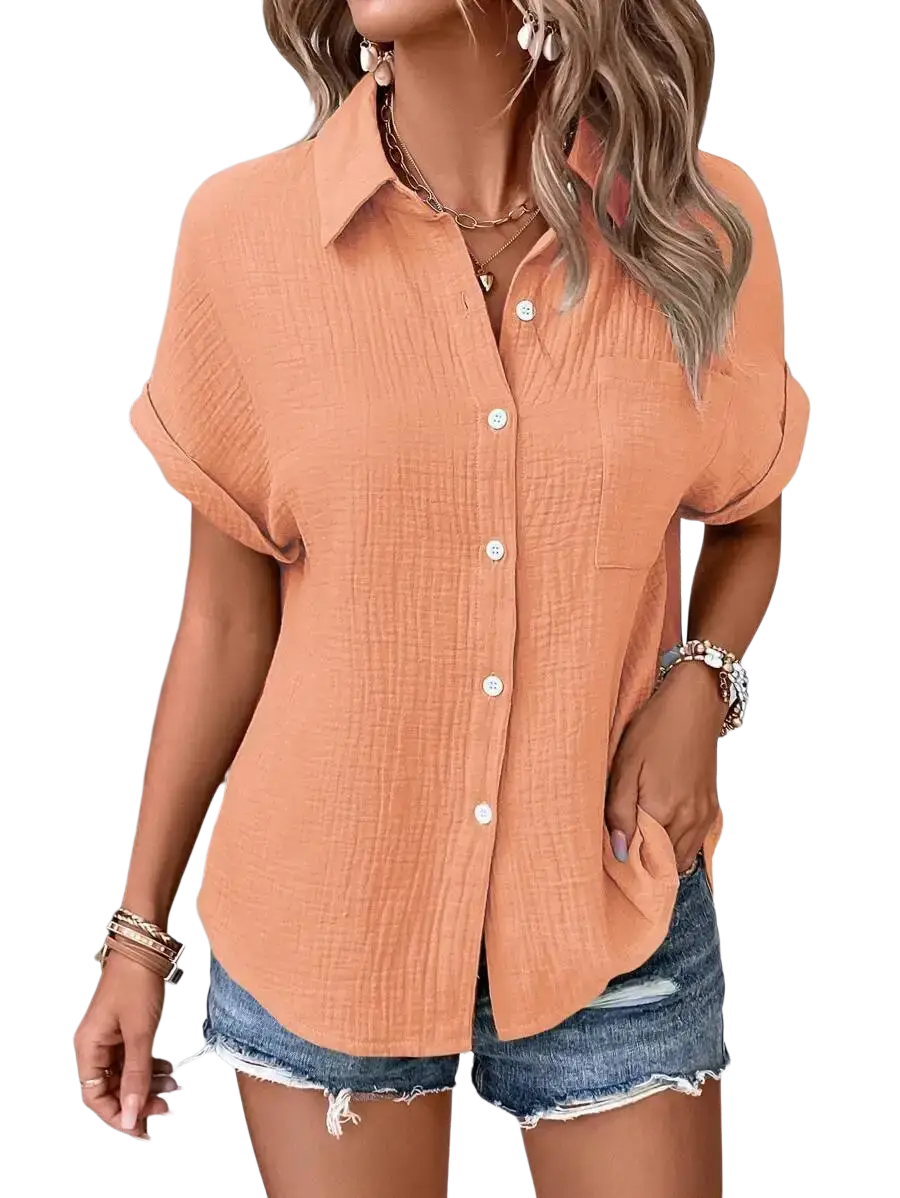 A soft peach-colored women cotton short sleeve button up shirt with subtle texture and rolled cuffs