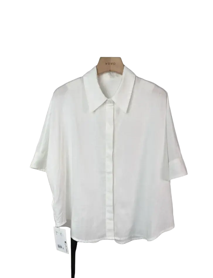 White linen short-sleeved button-up shirt with classic collar hanging on wooden hanger for women