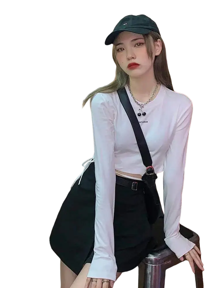 Black crossbody bag with a single shoulder strap and red circular buckle shown with women long sleeve crisscross crop top
