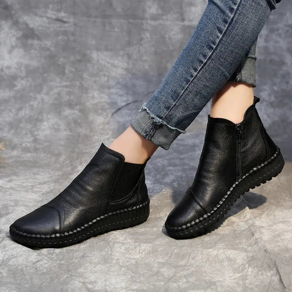 Black leather ankle boots with textured surface and visible stitching along the sole for winter wear