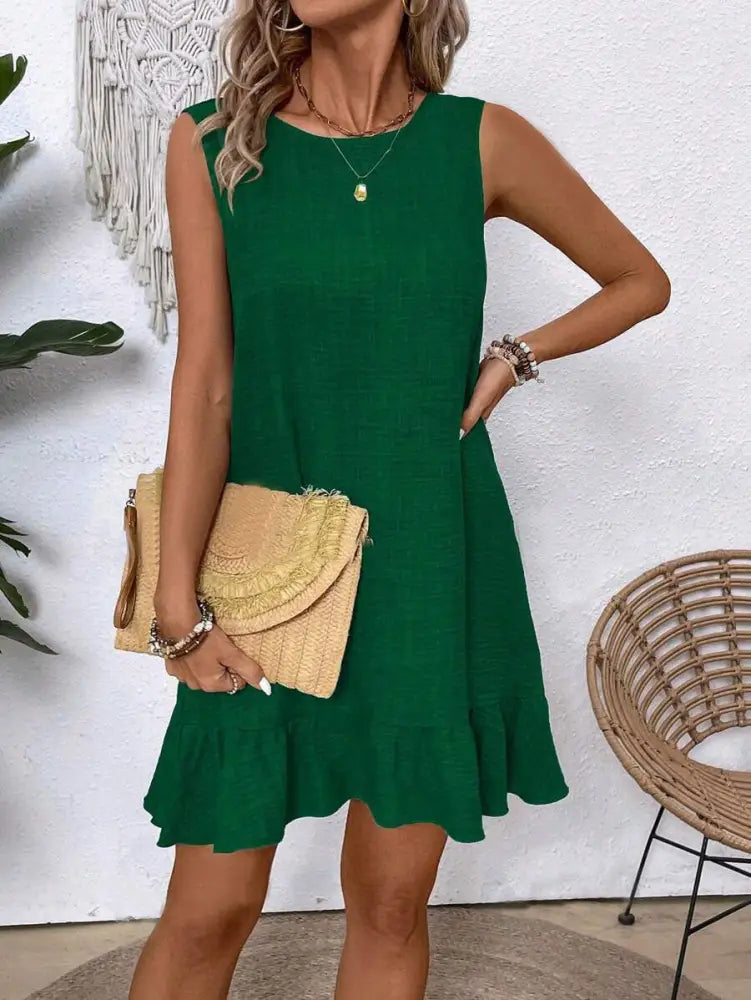 A sleeveless emerald green summer vacation beach dress with a flared skirt and ruffled hem