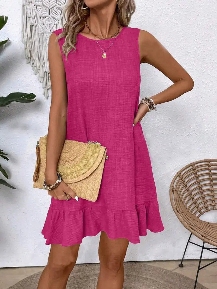 A vibrant fuchsia sleeveless summer vacation beach dress with ruffled hem and textured fabric
