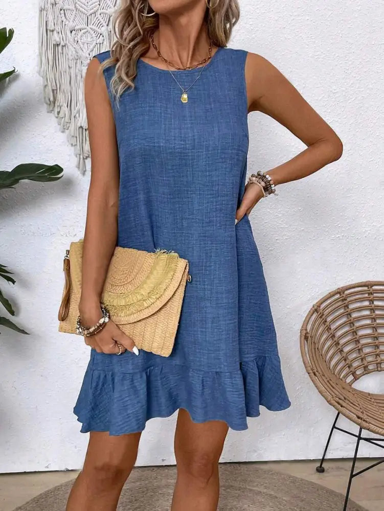 Blue sleeveless denim dress with ruffled hem and subtle texture designed for summer vacation beach wear