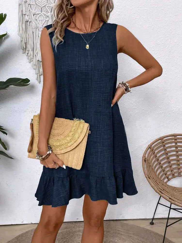 A navy blue sleeveless summer dress with textured fabric and ruffled hemline perfect for beach vacations