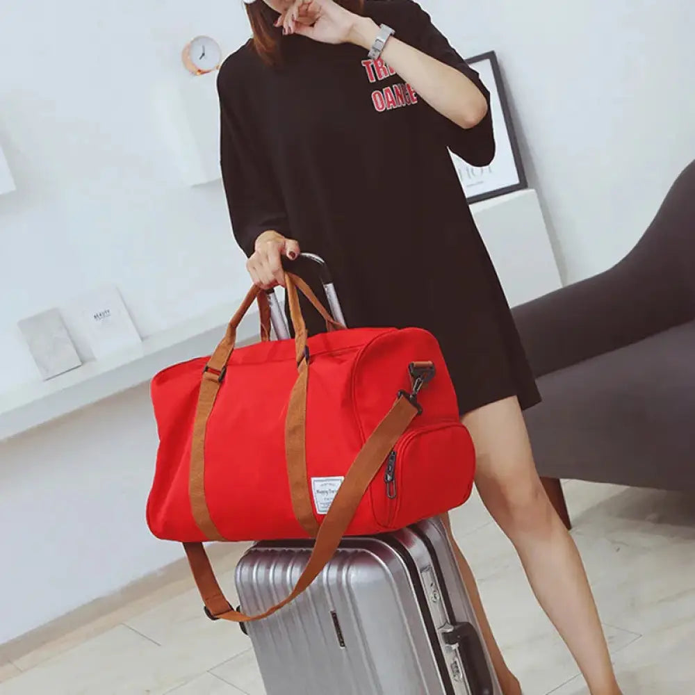 Red canvas duffel bag with brown leather handles and shoulder strap for women’s gym and weekend travel use