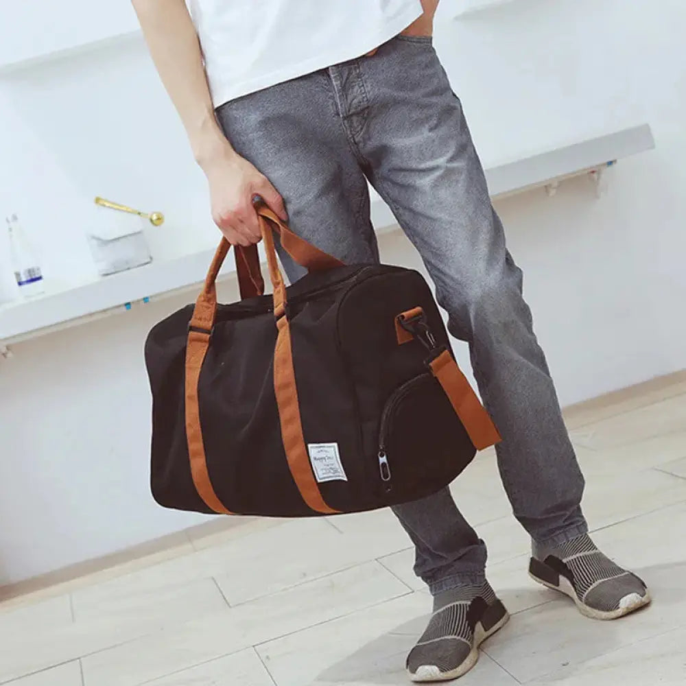 Black canvas women’s gym and weekend travel duffel bag with tan leather handles and trim