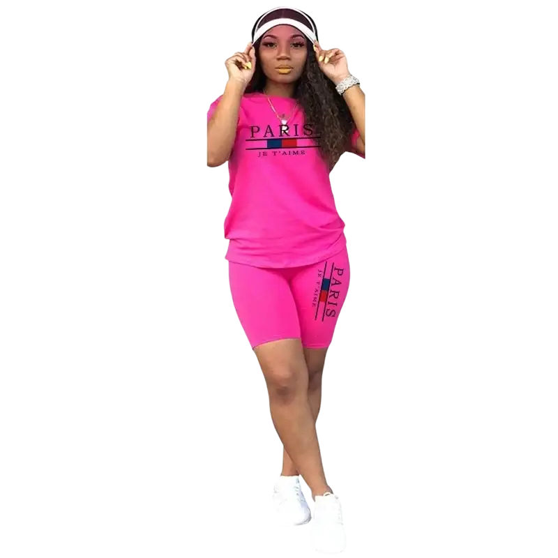 Bright pink women two piece tracksuit with pullover closure featuring short sleeve top and bike shorts with black lettering