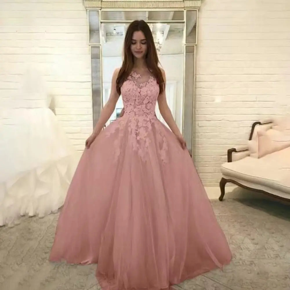 A soft pink sleeveless wedding gown with intricate lace bodice and flowing tulle skirt for floral elegance