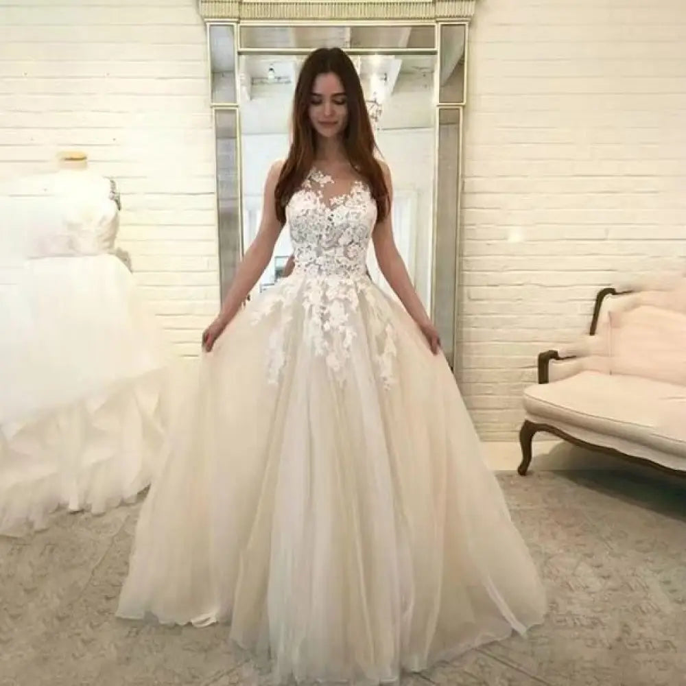 A woman wears an elegant ivory sleeveless lace and tulle floral wedding gown with intricate lace appliqués and a voluminous skirt