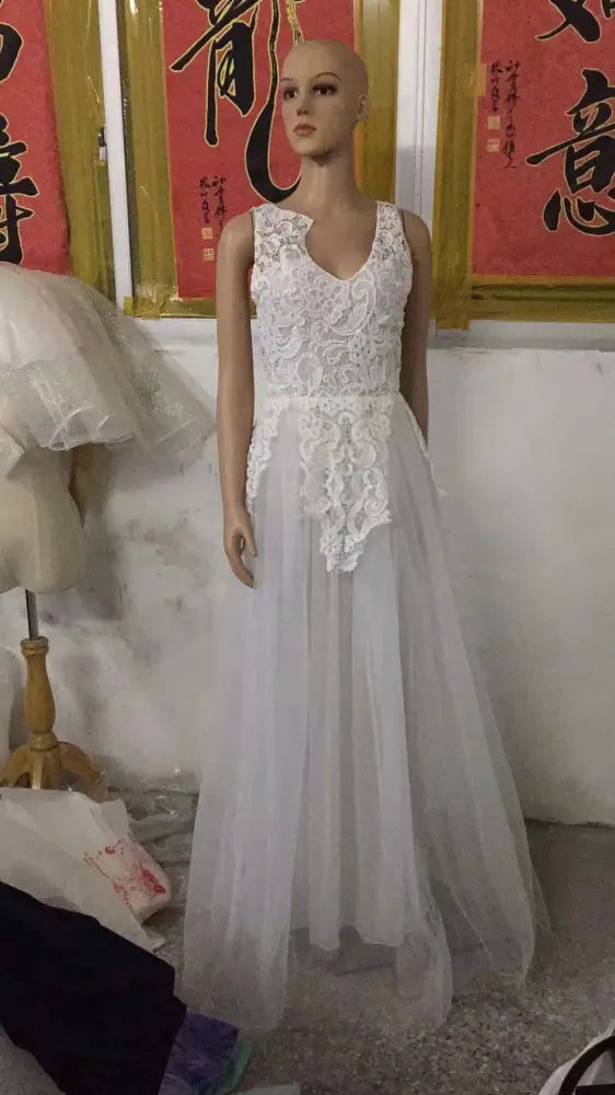 A white sleeveless lace and tulle floral wedding gown with a fitted bodice and flowing skirt