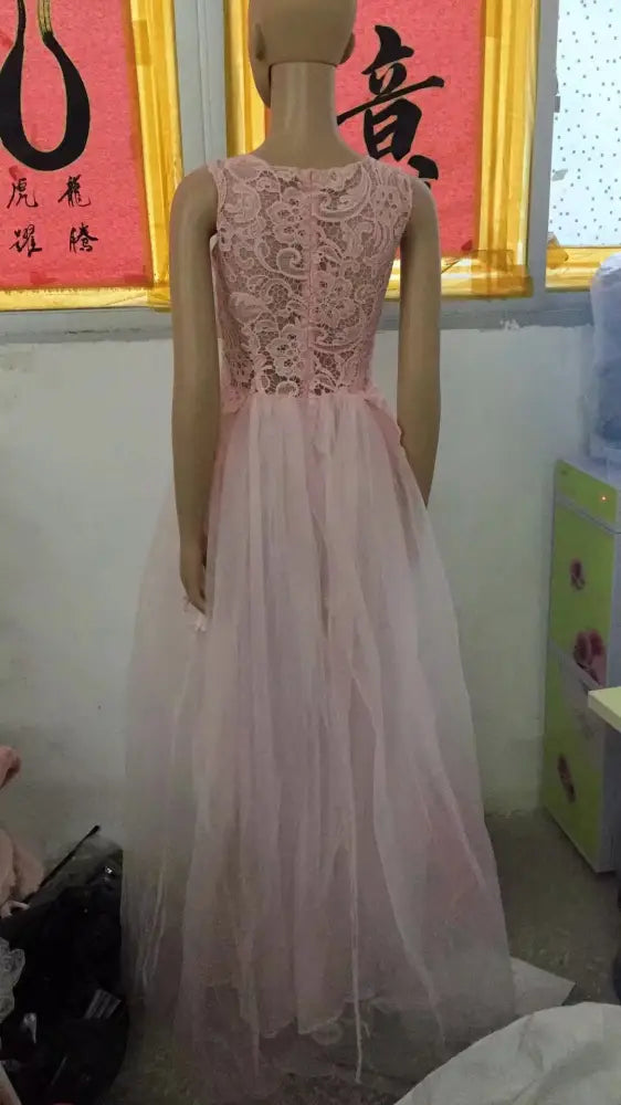 A delicate pink sleeveless floral wedding gown made of lace and tulle with a fitted bodice and flowing skirt