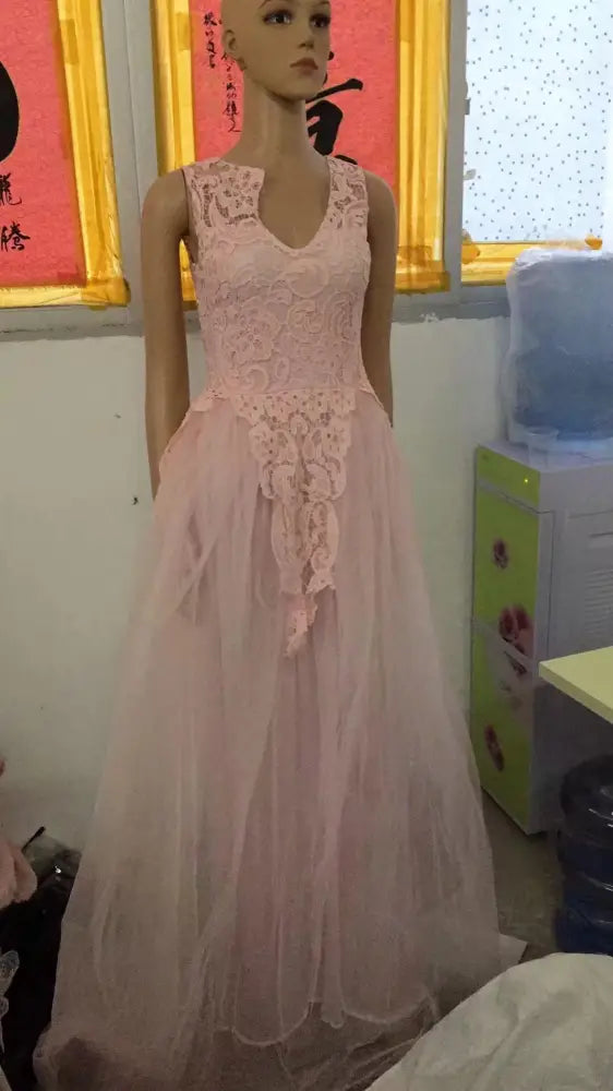 A delicate pink sleeveless lace and tulle floral wedding gown with fitted bodice and flowing skirt on a mannequin