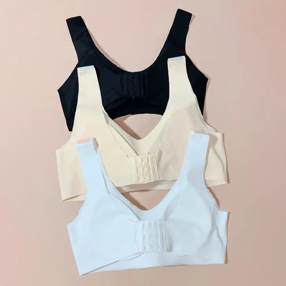 Three seamless underwire-free sports wide strap push up bras in black beige and light blue on soft pink background