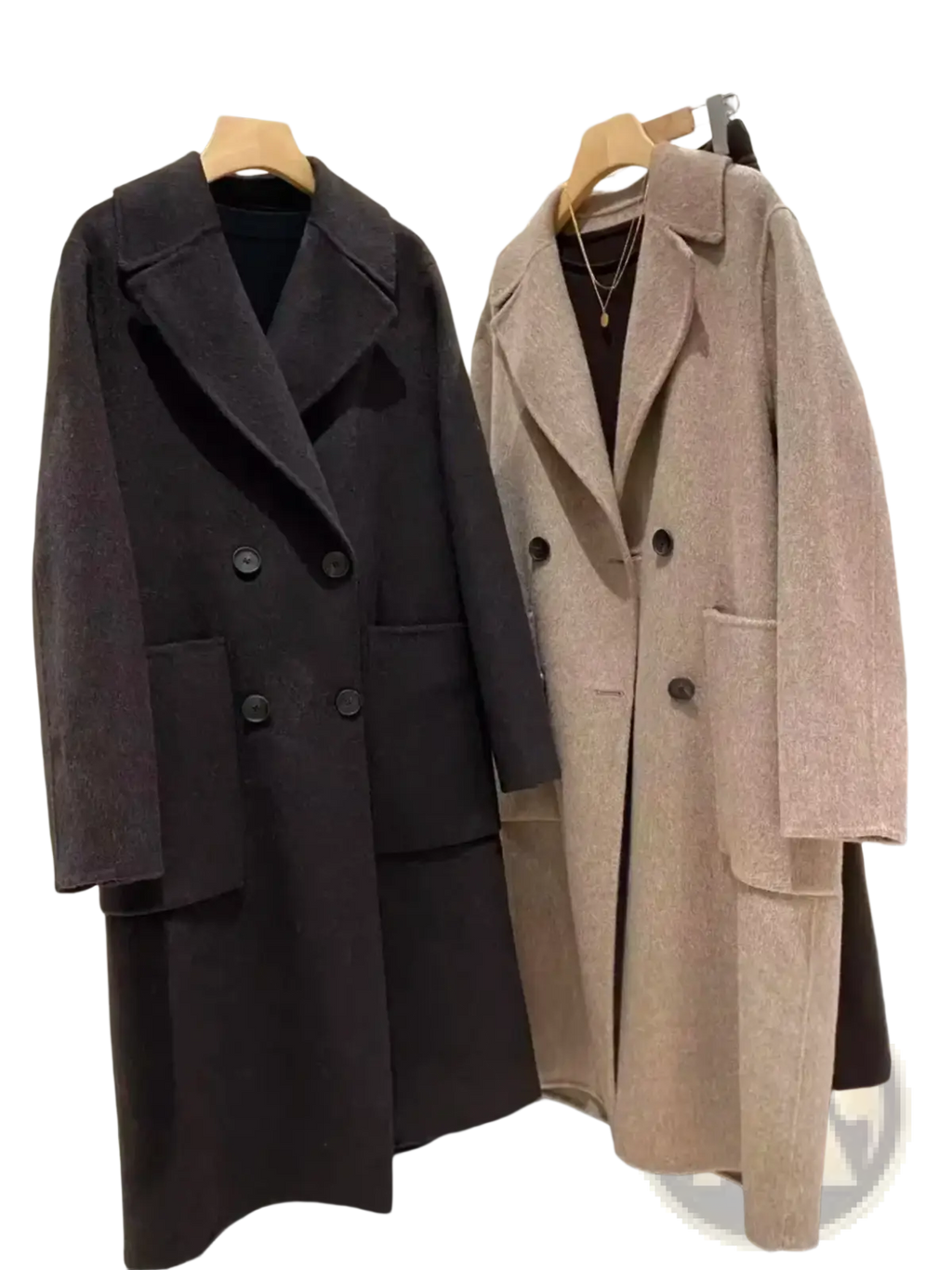 Two double-breasted wool overcoats in beige and dark charcoal hanging on wooden hangers for women