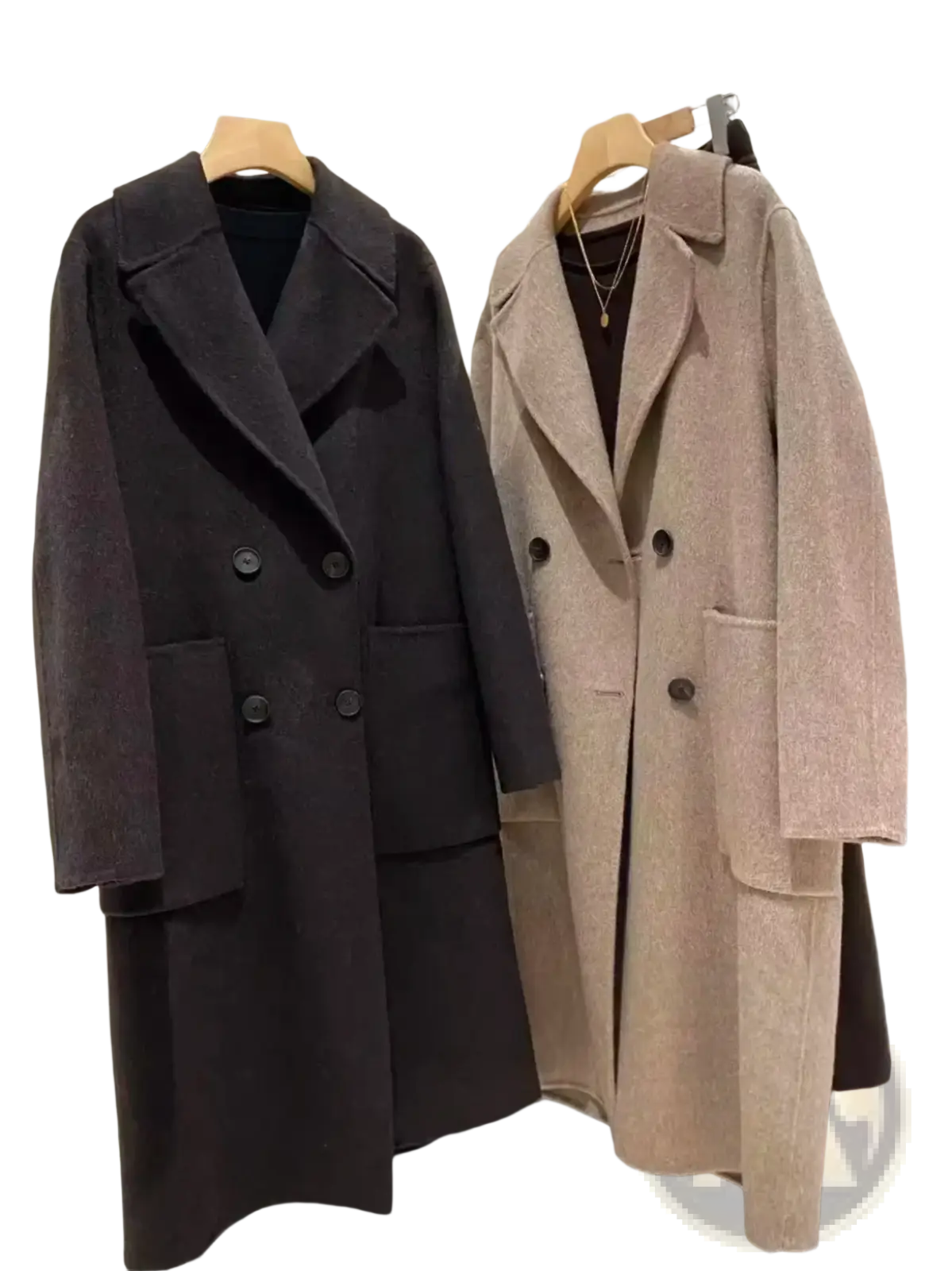 Two double-breasted wool overcoats in beige and dark charcoal hanging on wooden hangers for women