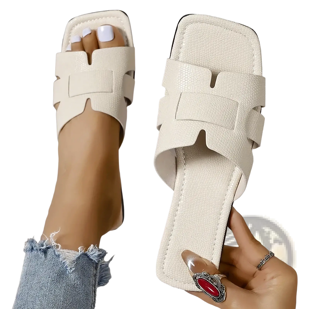 Cream-colored womens flat slide sandals with square toe, textured faux leather upper, and black rubber sole for casual summer wear