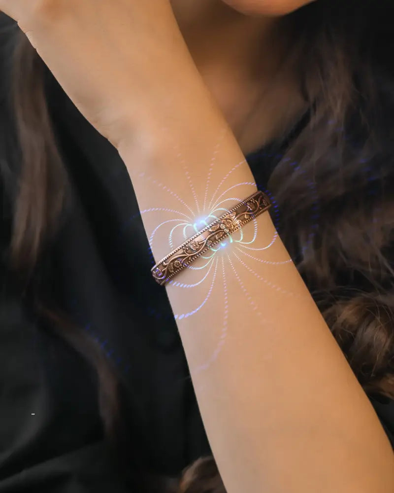 Floral copper magnetic therapy bangle bracelet in bronze metal with intricate floral engravings worn on a wrist