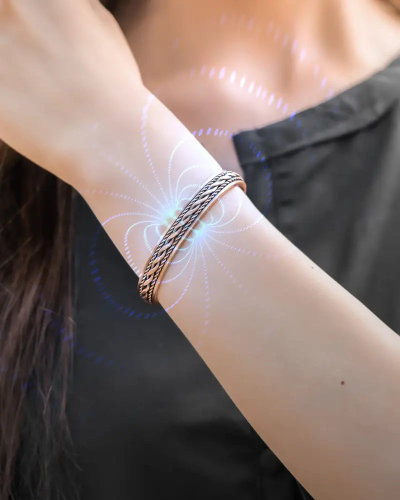 A sleek silver-toned copper magnetic therapy braided bangle bracelet with a textured woven metal design for women