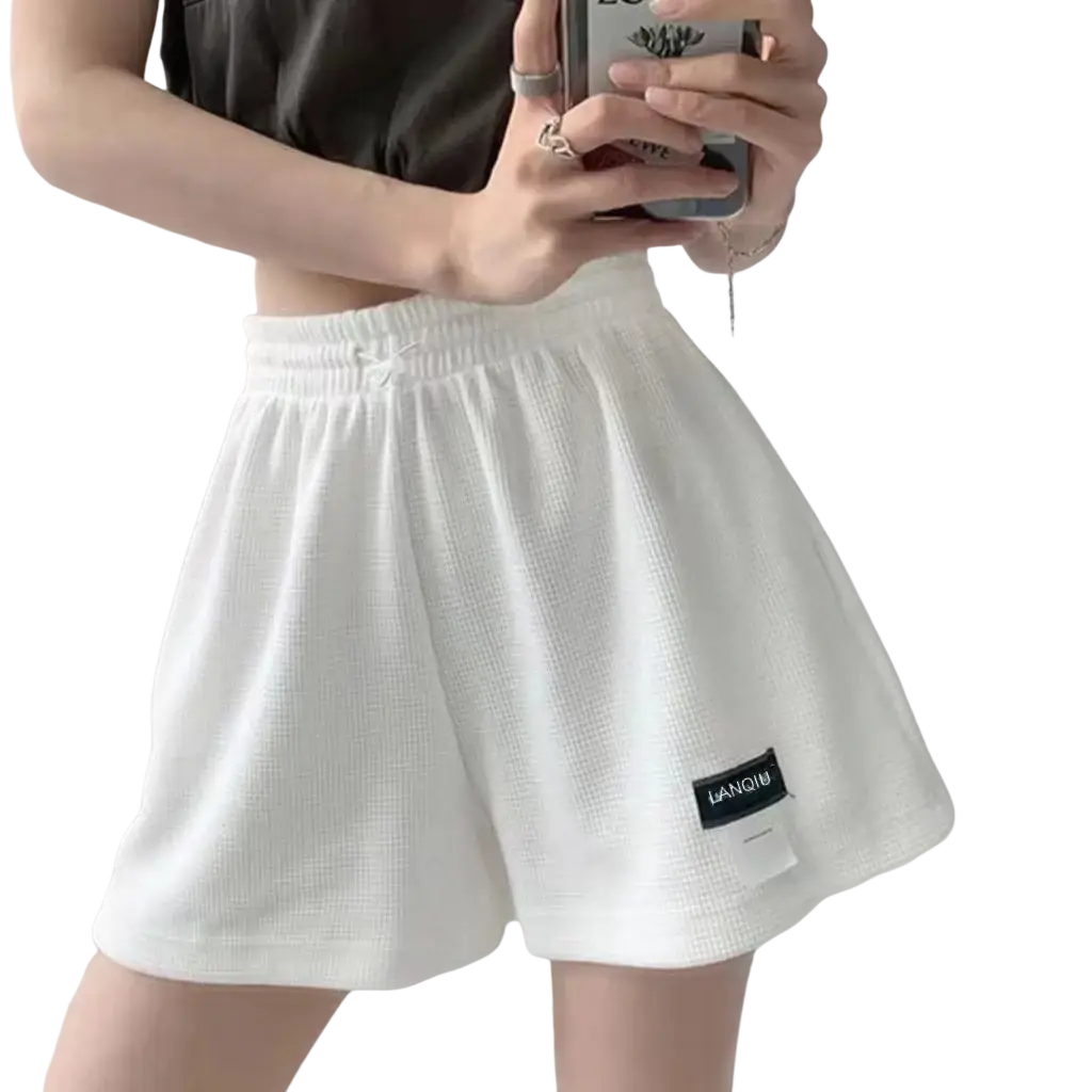 Women’s white knit shorts with high waist and textured main fabric composition featuring a black brand patch