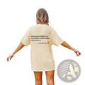 Back view of a cream-colored women’s oversized cotton t-shirt with a black slogan print graphic