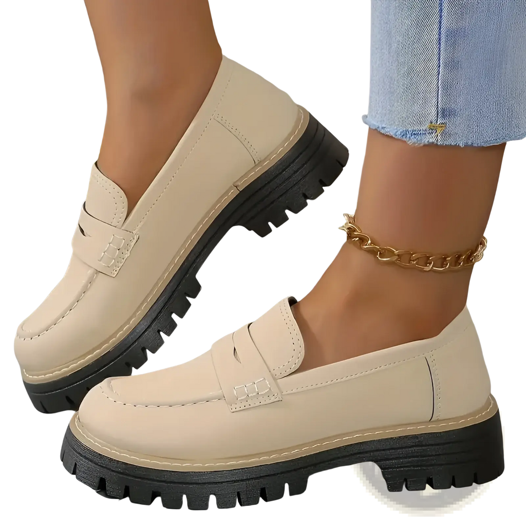 Cream-colored leather women’s platform loafers with black chunky soles and decorative toe strap for casual wear